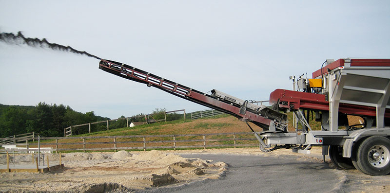 Conveyor arm spraying stone at dusk