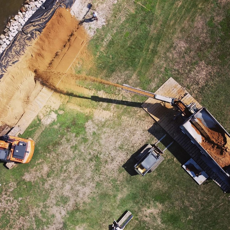 Aerial view of a stone slinger truck placing sand on grade