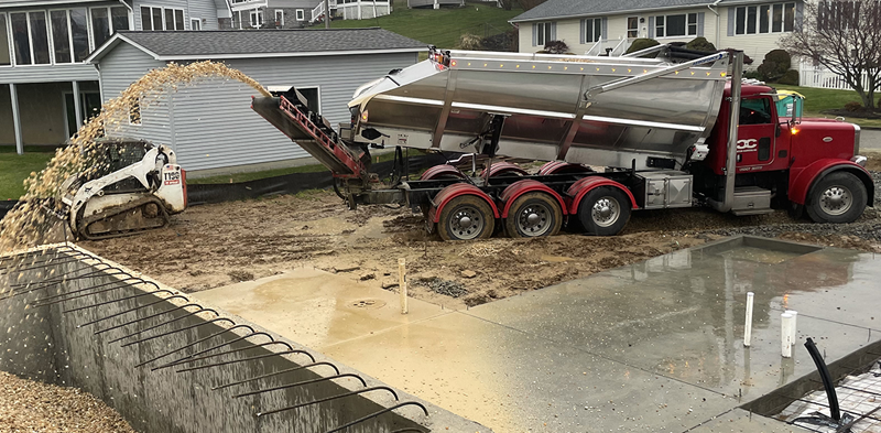 Truck placing fresh gravel on a residential driveway